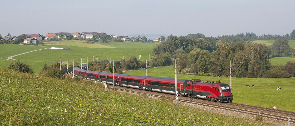 Railjet travels trhrough scenic landscape